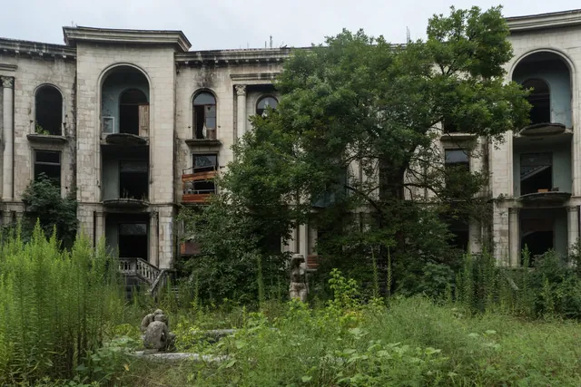 Façade of Sanatorium Medea and statues in the undergrowth